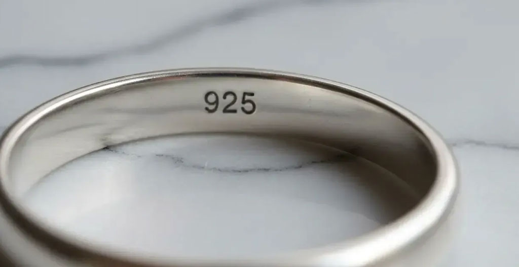 Macro détail d'une pierre de lune cabochon sur bague argent 925 montrant les inclusions naturelles et le poinçon gravé